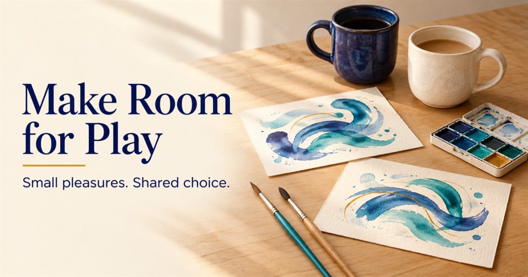 Two abstract teal-and-indigo watercolor paintings, brushes, a small palette and two mugs on a wooden table.